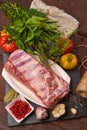 Raw pork meat on a slate stone plate with spices, colorful tomatoes and red currant on a wooden rustic background. Top view Royalty Free Stock Photo