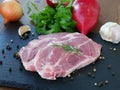 Raw pork neck boneless collar slices over slate platter with vegetables Royalty Free Stock Photo