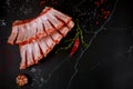 Raw pork ribs with herbs, garlic and pepper on black background Royalty Free Stock Photo