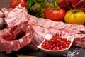 Raw pork ribs on a slate stone plate with spices, colorful tomatoes and red currant on a wooden rustic background Royalty Free Stock Photo