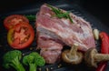 Raw pork ribs with vegetables, tomato sliced, shiitake, broccoli and red chili in black grill pan Royalty Free Stock Photo