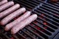 Raw Pork sausages grilling on BBQ on a summer picnic, close up of the grill, meat and fire.Grilled sausages on grill with smoke Royalty Free Stock Photo