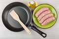 Raw pork sausages in plate, frying pan with spatula Royalty Free Stock Photo