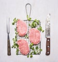 Raw pork steak on the grill with spinach and vintage knife and fork wooden rustic background top view