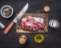 Raw pork steak with herbs, oil knife for meat on a cutting board on wooden rustic background top view close up Royalty Free Stock Photo