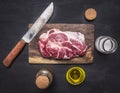 Raw pork steak with herbs, oil knife for meat on a cutting board wooden rustic background top view close up Royalty Free Stock Photo