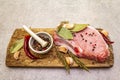 Raw pork steak with spices and dried herbs on vintage wooden board. Salt, garlic, hot pepper, rosemary, bay leaf with ceramic Royalty Free Stock Photo