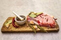 Raw pork steak with spices and dried herbs on vintage wooden board. Salt, garlic, hot pepper, rosemary, bay leaf with ceramic Royalty Free Stock Photo