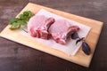 Raw pork steak with spices Leaves of coriander on wooden cutting board. Ready for cooking.