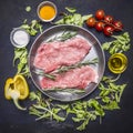 Raw pork steak on vintage frying pan salad, cherry tomatoes, bell pepper, oil spices wooden rustic background top view Royalty Free Stock Photo