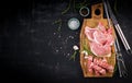 Different types of raw pork meat and chopped sausages ÃÂ¾n the dark table.