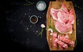 Different types of raw pork meat and chopped sausages ÃÂ¾n the dark table.