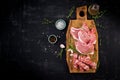 Different types of raw pork meat and chopped sausages ÃÂ¾n the dark table.