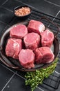 Raw pork tenderloin medallions steaks on a kitchet tray with thyme and sea salt. Black background. Top view Royalty Free Stock Photo