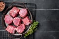 Raw pork tenderloin medallions steaks on a kitchet tray with thyme and sea salt. Black background. Top view. Copy space Royalty Free Stock Photo