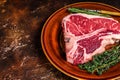 Raw porterhouse beef meat Steak with herbs on a plate. Dark background. Top view. Copy space Royalty Free Stock Photo