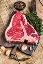 Raw Porterhouse or T-bone beef meat Steak with herbs on a wooden cutting board. wooden background. Top view Royalty Free Stock Photo