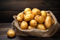 Raw potato harvest displayed in a vintage sack on wood