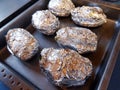 raw potatoes in aluminum foil prepared in the baking tray to be baked in the oven