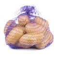 Raw potatoes in a blue net bag isolated on white background Royalty Free Stock Photo