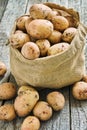 Raw potatoes in a burlap sack on the rough wooden boards Royalty Free Stock Photo