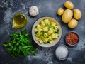 raw potatoes with white garlic, parsley and small bowl with oil on the kitchen table