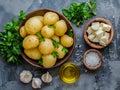 raw potatoes with white garlic, parsley and small bowl with oil on the kitchen table