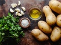 raw potatoes with white garlic, parsley and small bowl with oil on the kitchen table