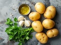 raw potatoes with white garlic, parsley and small bowl with oil on the kitchen table