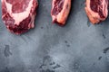 Raw prime beef meat dry aged steak, tomahawk, t bone or porterhouse and club steak, on gray stone background, top view flat lay, Royalty Free Stock Photo