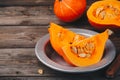 Raw pumpkin slices with seeds on a wooden background.