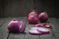 Raw purple onions, one cut, on wooden table