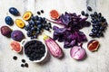 Raw purple vegetables and fruits on gray concrete background. Flat lay of purple food. Eggplant, grapes, figs, plums, blackberries