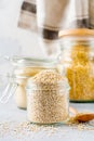 Raw quinoa grains in jar. Healthy vegetarian food on gray kitchen table.