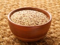 Raw Quinoa in wooden bowl, superfood. Brown sisal mat background, side view.