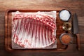 Raw rack of lamb ribs on white cooking paper and wooden cutting table Royalty Free Stock Photo