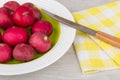 Raw radishes in glass plate and knife on napkin