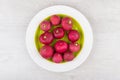 Raw radishes in green glass plate on wooden table