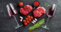 Raw ramp beef cuts with herbs and red wine glasses over black textured background top view, big size Royalty Free Stock Photo