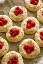 Raw raspberry sweet buns prepared for baking on baking paper, close up view.