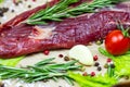 Raw red beef meat with green rosemary and fresh vegetables on light wooden cutting board background. Royalty Free Stock Photo