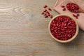 Raw red kidney beans with bowl, spoon and napkin on wooden table, flat lay. Space for text Royalty Free Stock Photo