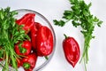 Raw red organic peppers with bunch of aromatic green spice parsley in a glass bowl ready to cook with Royalty Free Stock Photo