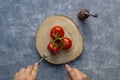 Raw red tomato eaten by a man hand on a wooden plate. Royalty Free Stock Photo
