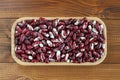 Raw red with white speckled kidney beans in bamboo plate on wooden background Royalty Free Stock Photo