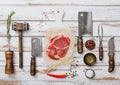 Raw rib eye steak on white wooden background. Fork,knife,meat cleavers with tenderizer and salt,pepper,pepper mill with various Royalty Free Stock Photo