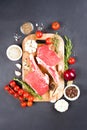 Raw ribeye beef steaks with seasonings on wooden cutting board over dark concrete background Royalty Free Stock Photo