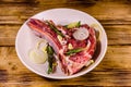 Raw ribeye steak, spices, rosemary, onion and garlic in a ceramic plate on wooden table Royalty Free Stock Photo