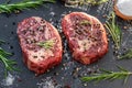 Raw Ribeye steaks with salt and herbs on grey board. Top view Royalty Free Stock Photo