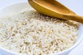 Raw rice in white plate and wooden spoon close up Royalty Free Stock Photo